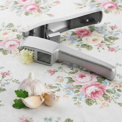 "Utilisation du presse-ail en aluminium pour écraser une gousse d'ail entière sans effort et sans odeur sur les mains."